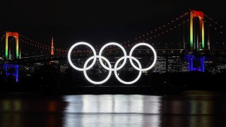 The Olympic rings lit up at night in front of Tokyo's Rainbow Bridge