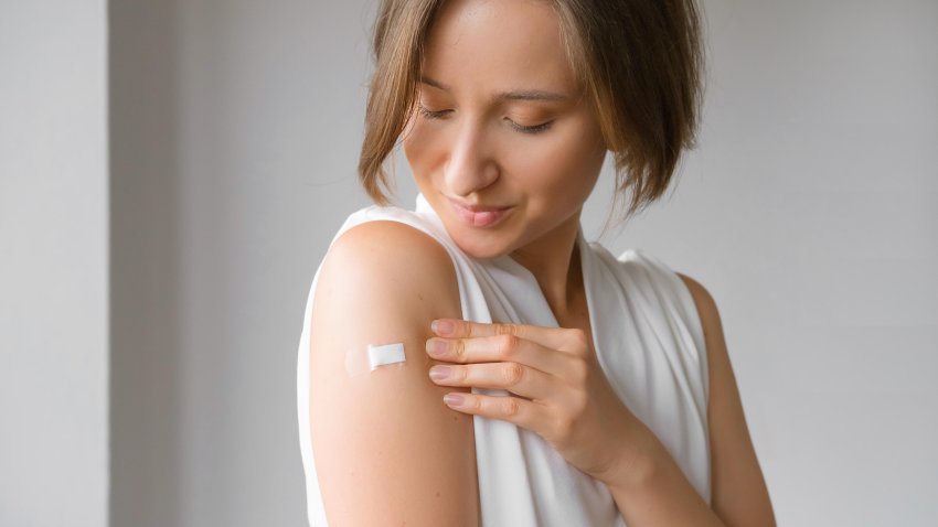 Smiling Vaccinated Woman Showing Arm With Medical Patch Plaster After Covid-19 Vaccine Injection. Coronavirus Vaccination Advertisement Campaign. Vaccine Done