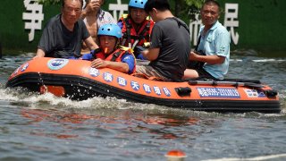 Rescuers evacuate stranded people in the waterlogged urban area of Weihui City in Xinxiang, central China’s Henan Province, July 27, 2021.
