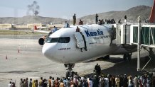 Afghan people climb atop a plane as they wait at the Kabul airport in Kabul on August 16, 2021, after a stunningly swift end to Afghanistan's 20-year war, as thousands of people mobbed the city's airport trying to flee the group's feared hardline brand of Islamist rule.