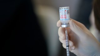 a worker readies syringes with the Moderna COVID-19 vaccine