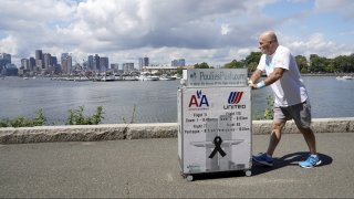 Paul Veneto pushes a beverage cart along the Boston harbor, Saturday, Aug. 21, 2021