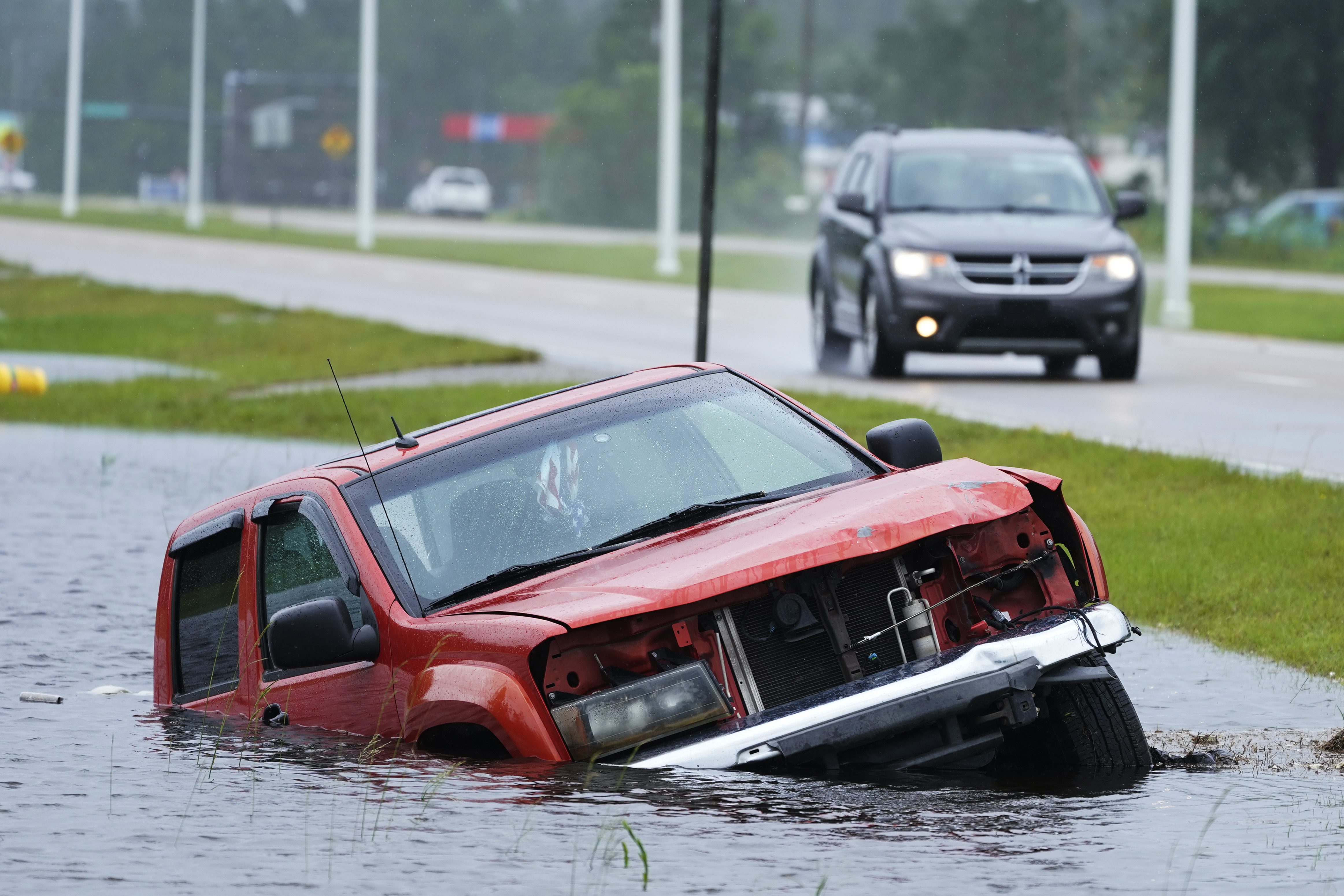 An abandoned vehicle is half-submerged in a ditch next to a near flooded highway as the outer bands of Hurricane Ida arrive Sunday, Aug. 29, 2021, in Bay Saint Louis, Miss.