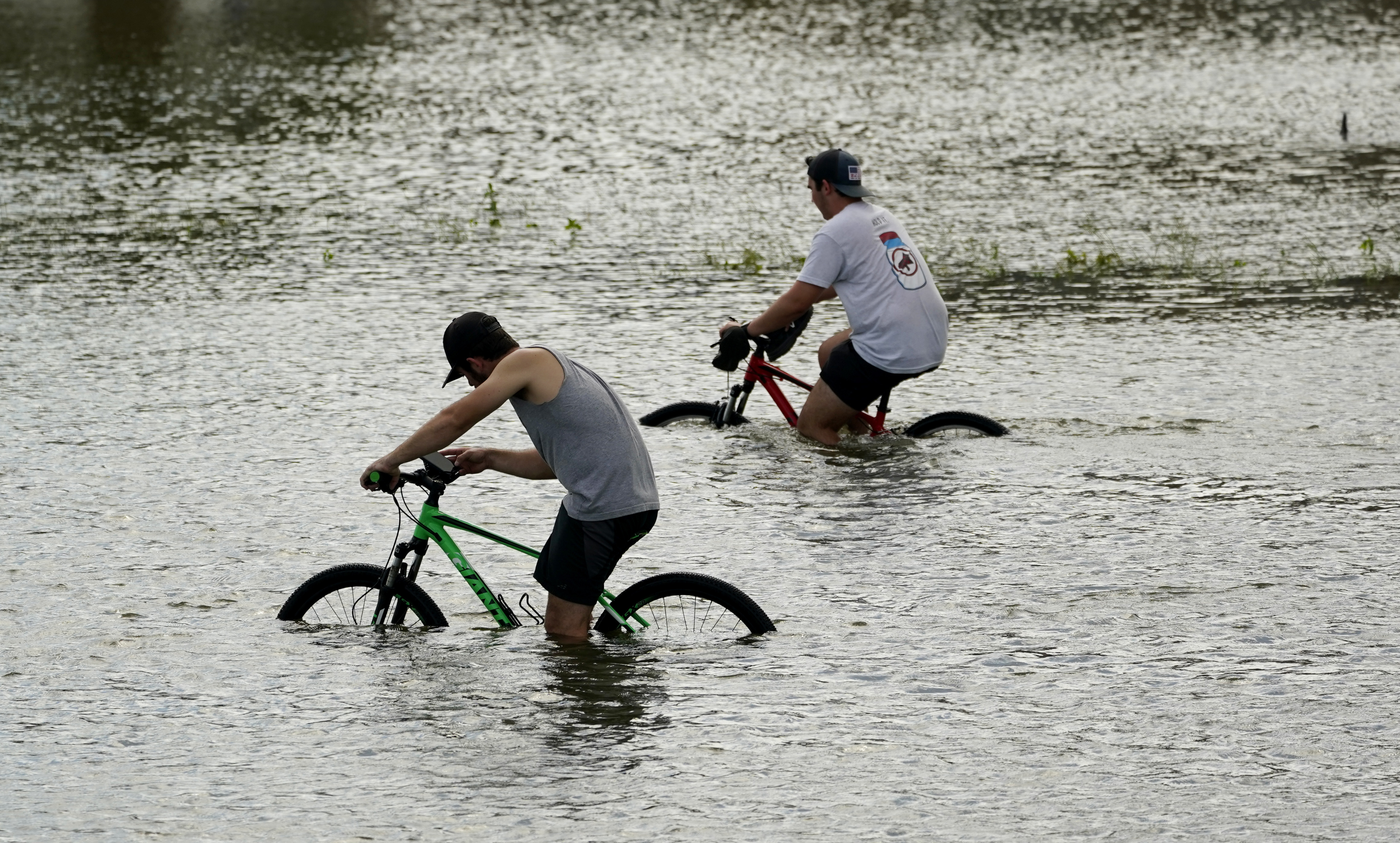 Cyclists peddle through floodwaters caused by the effects of Hurricane Ida near the New Orleans Marina, Monday, Aug. 30, 2021, in New Orleans, La.