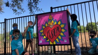 Children from the Boys & Girls Club of Vista pose with a painting featuring the city's name.