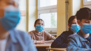 Students sitting and wearing a face mask in class.