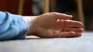 File image of the hand of an elderly man lying on the floor.