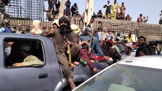 Taliban fighters sit on a vehicle along the street in Jalalabad province