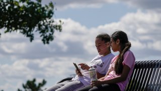 Savannah Brown and Glendy Stollberg use their phone in Kilbourn Reservoir Park