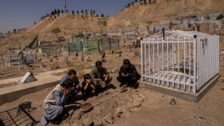 the Ahmadi family pray at the cemetery next to family graves of family members killed by a US drone strike, in Kabul, Afghanistan