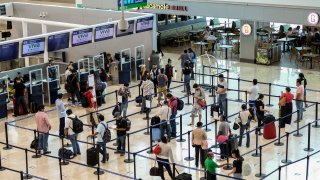 tourists wait to check in at the airport in Cancun, Mexico