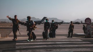 A Marine assigned to the 24th Marine Expeditionary Unit (MEU) escorts Department of State personnel to be processed for evacuation at Hamid Karzai International Airport, in Kabul, Afghanistan, Sunday, Aug. 15, 2021.