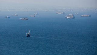 An oil platform and cargo container ships offshore along the coastline are pictured.