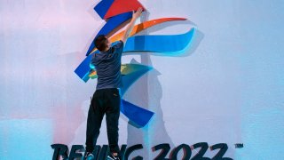A crew member leaps to fix a logo for the 2022 Beijing Winter Olympics