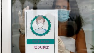 Business owner putting Mandatory use of face mask sign at shop