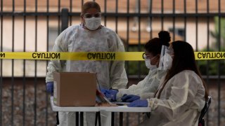 Healthcare workers work at a mobile COVID-19 testing site in Paramount, Calif., Wednesday, Jan. 12, 2022.