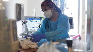 A healthcare worker treats a patient on the Covid-19 ICU floor of the University of Massachusetts (UMass) Memorial Hospital