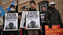 Activists hold placards saying BBC Don't Sportswash Genocide