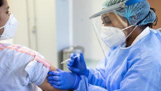 A doctor or nurse vaccinating a patient with a syringe