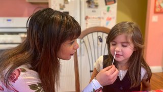 A mother is conducting a COVID-19 at-home test on her child.