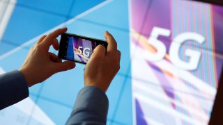 A journalist uses his mobile phone to take a picture of the 5G logo prior to the auction of spectrum for 5G services at the Bundesnetzagentur headquarters in Mainz, Germany, March 19, 2019.