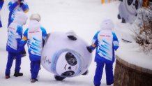 Volunteers carry an inflatable of Bing Dwen Dwen, the mascot of the 2022 Winter Olympics, at the sliding center, Feb. 13, 2022, in the Yanqing district of Beijing, China.