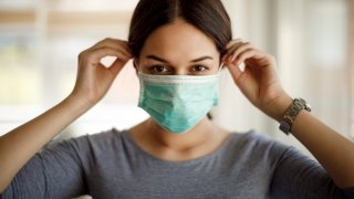 Portrait of young woman putting on a protective mask