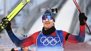 Norway's Johannes Thingnes Boe celebrates winning Gold in the Biathlon Men's 15km Mass Start event, Feb. 18, 2022, at the 2022 Winter Olympic Games.