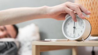 Image of a man turning off an alarm clock.