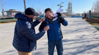 NBC 7 Media Manager Jason Guinter (left) assists NBC 7 Anchor Steven Luke with his mic while covering the Winter Olympics in Beijing, Feb. 10, 2022.