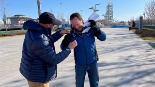 NBC 7 Media Manager Jason Guinter (left) assists NBC 7 Anchor Steven Luke with his mic while covering the Winter Olympics in Beijing, Feb. 10, 2022.