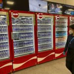 A woman walks by a row of drink coolers at a dining hall in Beijing, Feb. 8, 2022.