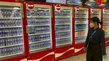 A woman walks by a row of drink coolers at a dining hall in Beijing, Feb. 8, 2022.