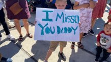 A young boy holds a sign that says, "I missed you daddy" while he waits for his father to return to San Diego with other U.S. Navy Sailors on Monday, Feb. 14, 2022.