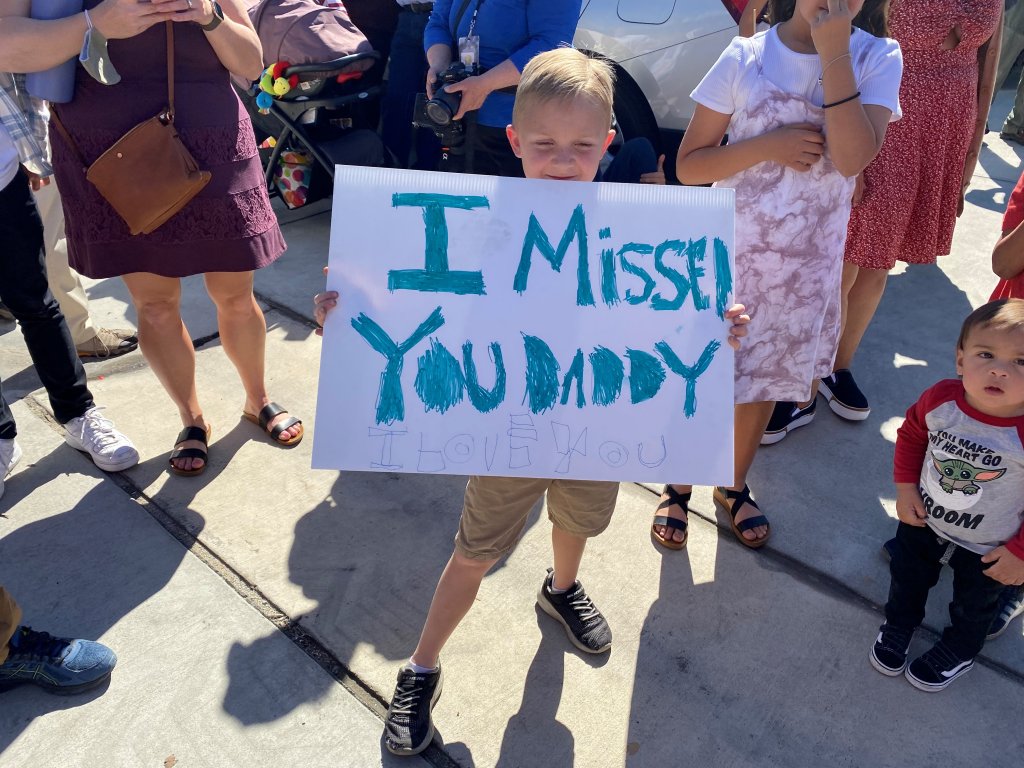A young boy holds a sign that says, "I missed you daddy" while he waits for his father to return to San Diego with other U.S. Navy Sailors on Monday, Feb. 14, 2022.