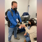 NBC 7 anchor Steven Luke (left) gets some help with dry hands from Miami Telemundo colleague Yari Domenech Del Valle, (right) in Beijing at the Winter Olympics, Feb. 10, 2022.