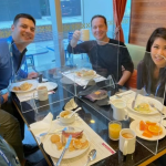 A group of four NBC employees, including NBC 7 anchor Steven Luke (upper right corner), gather for breakfast in a dining hall in Beijing at the Winter Olympics, Feb. 8, 2022.