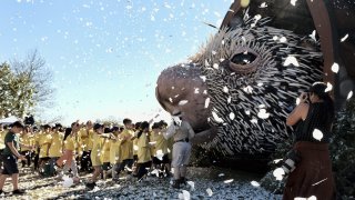 children run to see a giant puppet porcupine