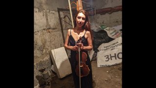 Vera Lytochenko holds her violin as she poses for a photo in a basement of an apartment building in Kharkiv, Ukraine, Sunday March 6, 2022.