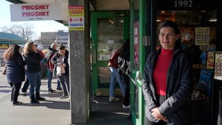 Olga Sagan, right, the owner of Russian bakery Piroshky Piroshky, poses for a photo in front of her business Wednesday, March 16, 2022, at Pike Place Market in Seattle. A recent caller threatened to stage a terrorist attack on the store. Angered by the deadly violence and the humanitarian crisis resulting from Russia's war on Ukraine, some people are taking it out on Russian businesses and brands in the U.S. and business owners and experts say it's the most intense anti-Russian sentiment they've seen to date.