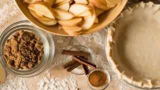 Close up of apples, spices and empty pie shell.