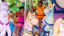 Two girls frolic on the carousel at Sesame Place San Diego in this promotional photograph.