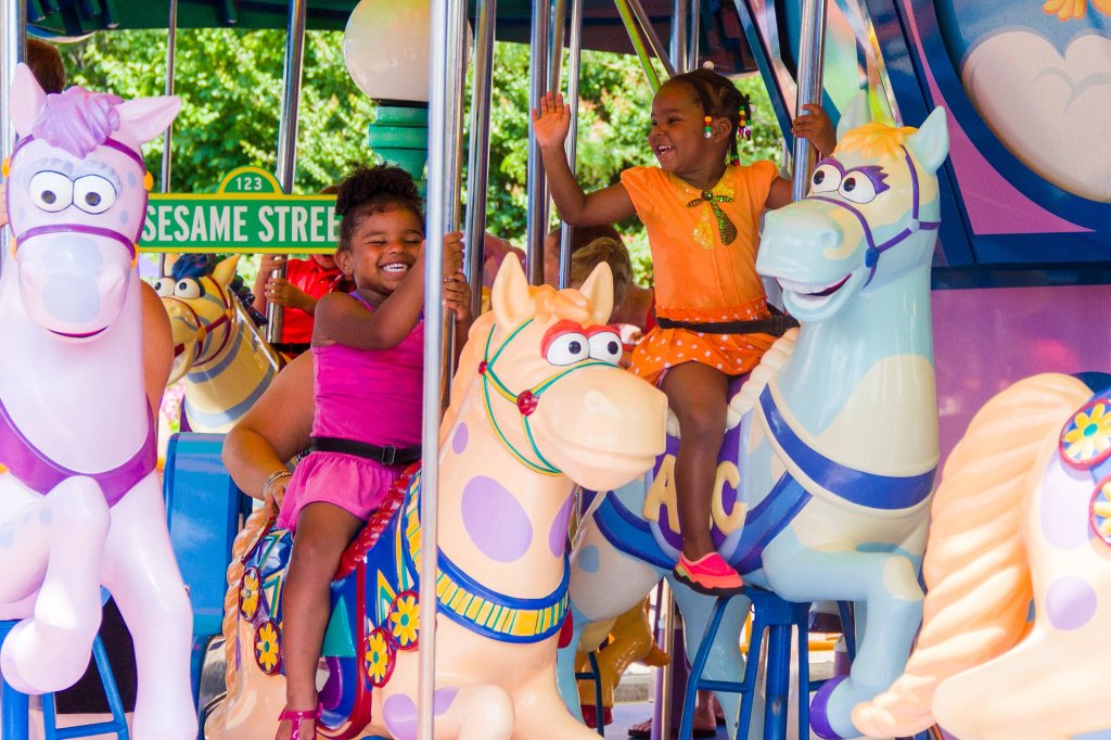 Two girls frolic on the carousel at Sesame Place San Diego in this promotional photograph.
