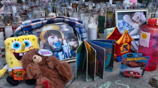 FILE - Photos, candles, flowers and balloons are placed as a memorial for three children who were killed at the Royal Villa apartments complex in the Reseda section of Los Angeles, April 12, 2021.