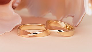 Pair of stylish gold wedding rings on beige background