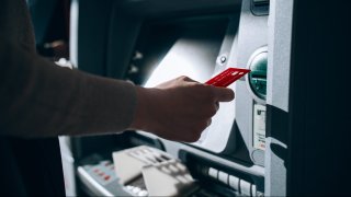 Close up of young woman inserting her bank card into automatic cash machine in the city. Withdrawing money, paying bills, checking account balances, transferring money. Privacy protection, internet and mobile security concept