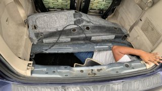 The arm of a man is seen inside a spare tire compartment during a search at the San Ysidro Port of Entry on April 1, 2022.