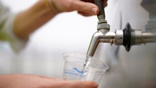 An official at the Carlsbad Desalination plant fills a cup with filtered water made from ocean water