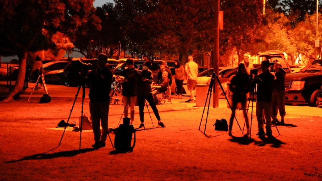 Photographers standing in a red glow from a blood moon lunar eclipse in San Diego