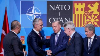 Turkish President Recep Tayyip Erdogan, center, shakes hands with NATO Secretary General Jens Stoltenberg